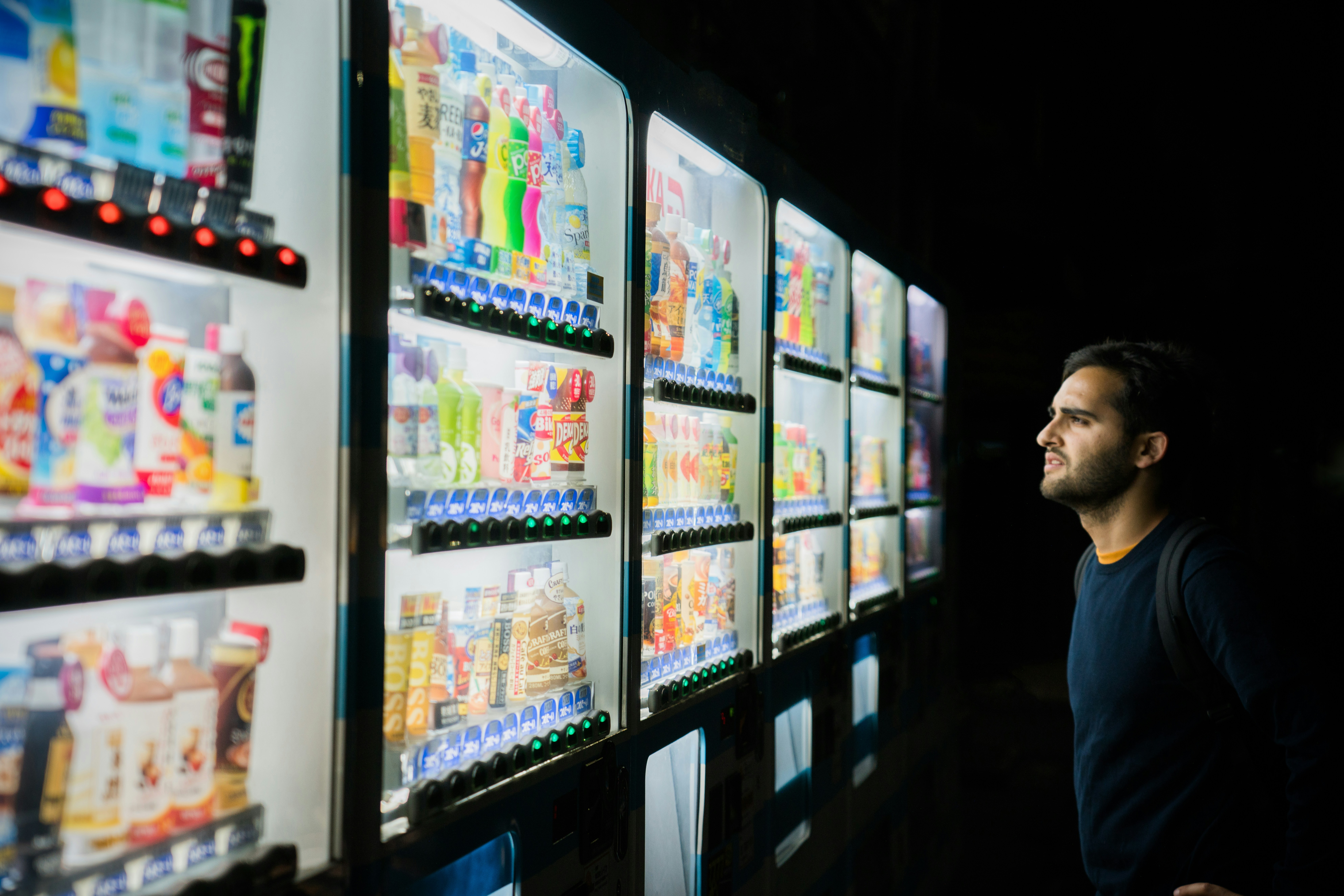 Person browsing a row of fully stocked modern vending machines